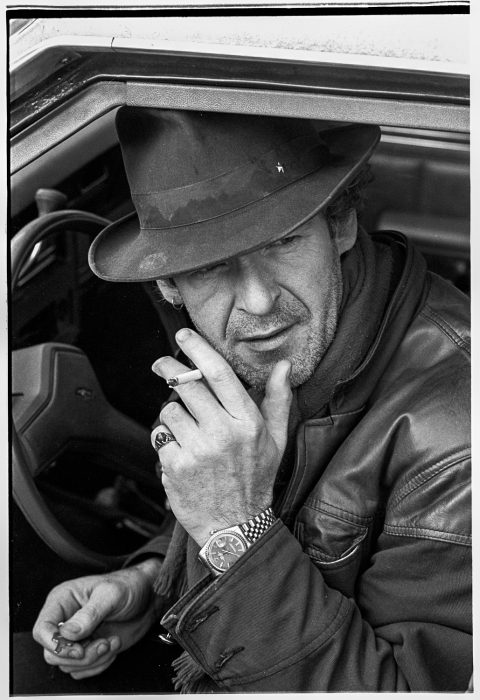 Rokende Peter Faber in auto met hoed